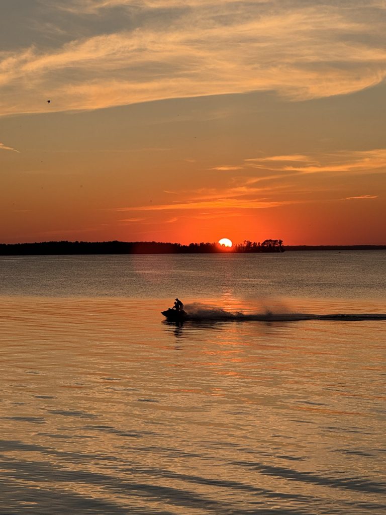 Туристы на водном мотоцикле на фоне садящегося солнца на Рыбинском водохранилище