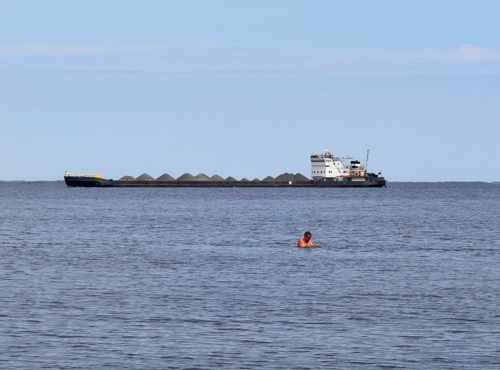 Баржа на Рыбинском водохранилище на фоне человек в воде, который занят чем-то интересным
